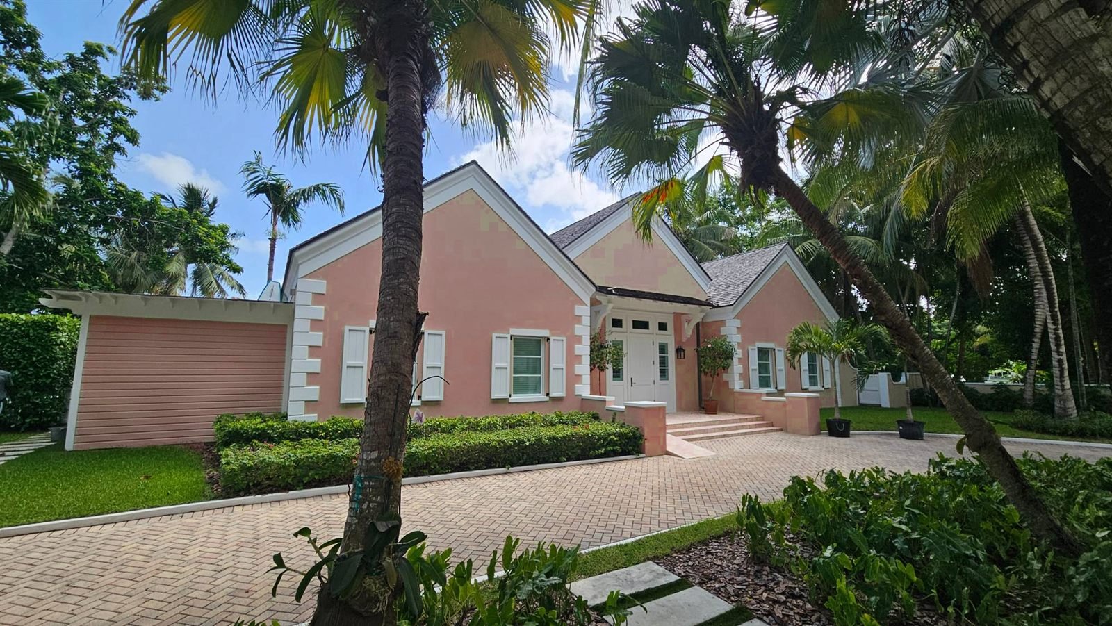 Single-storey home with white shutters and a brick driveway