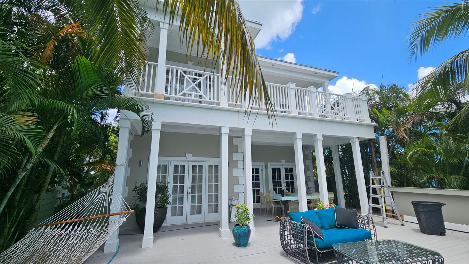 Two-storey home with white verandas and palm trees