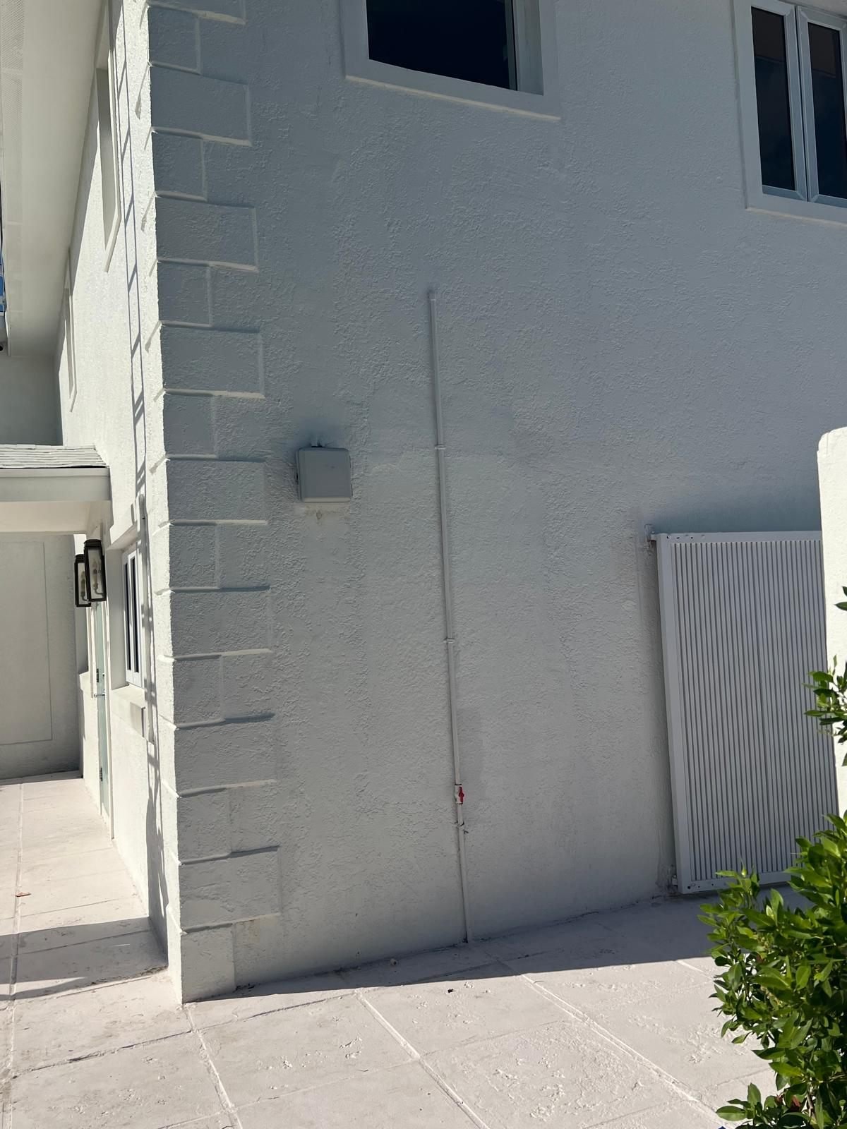 Exterior wall with a damp patch spreading beside a water line