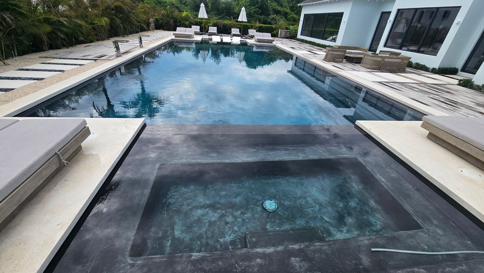 Dark-finish pool with sun shelf and loungers