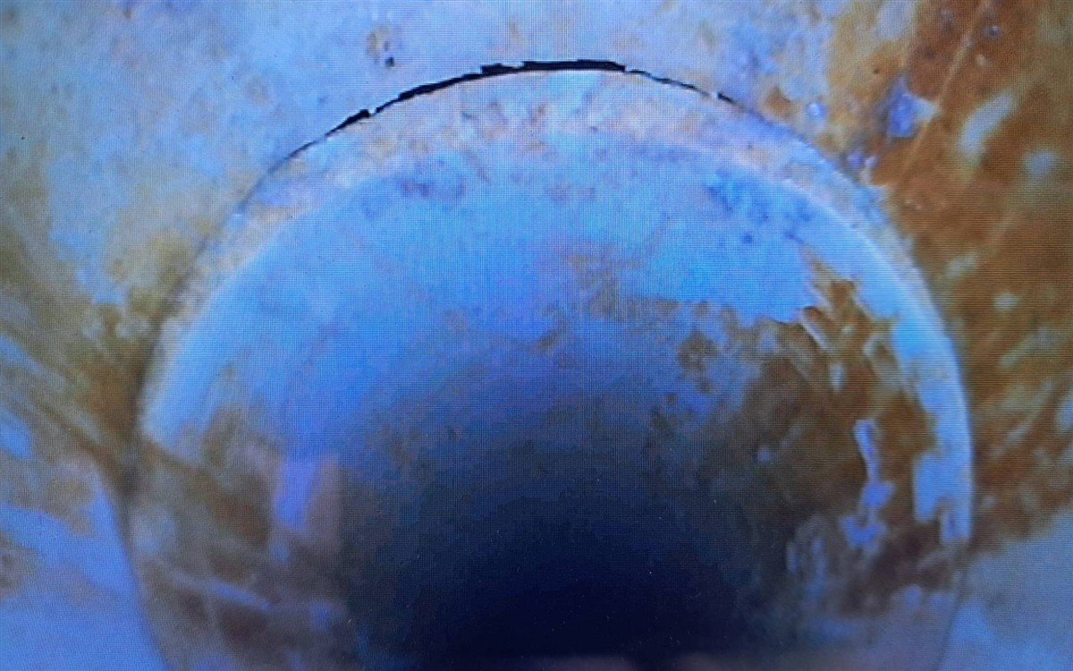Inspection camera view inside a pipe, showing a crack in the joint